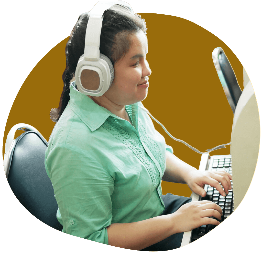 Side view of a person typing on a keyboard while wearing headphones.